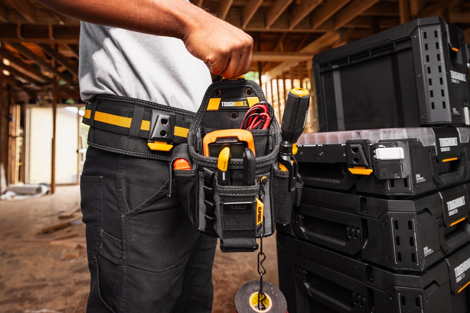 Muž drží puzdro ClipTech, ktoré ide pripnúť na lištu ToughBuilt StackTech.